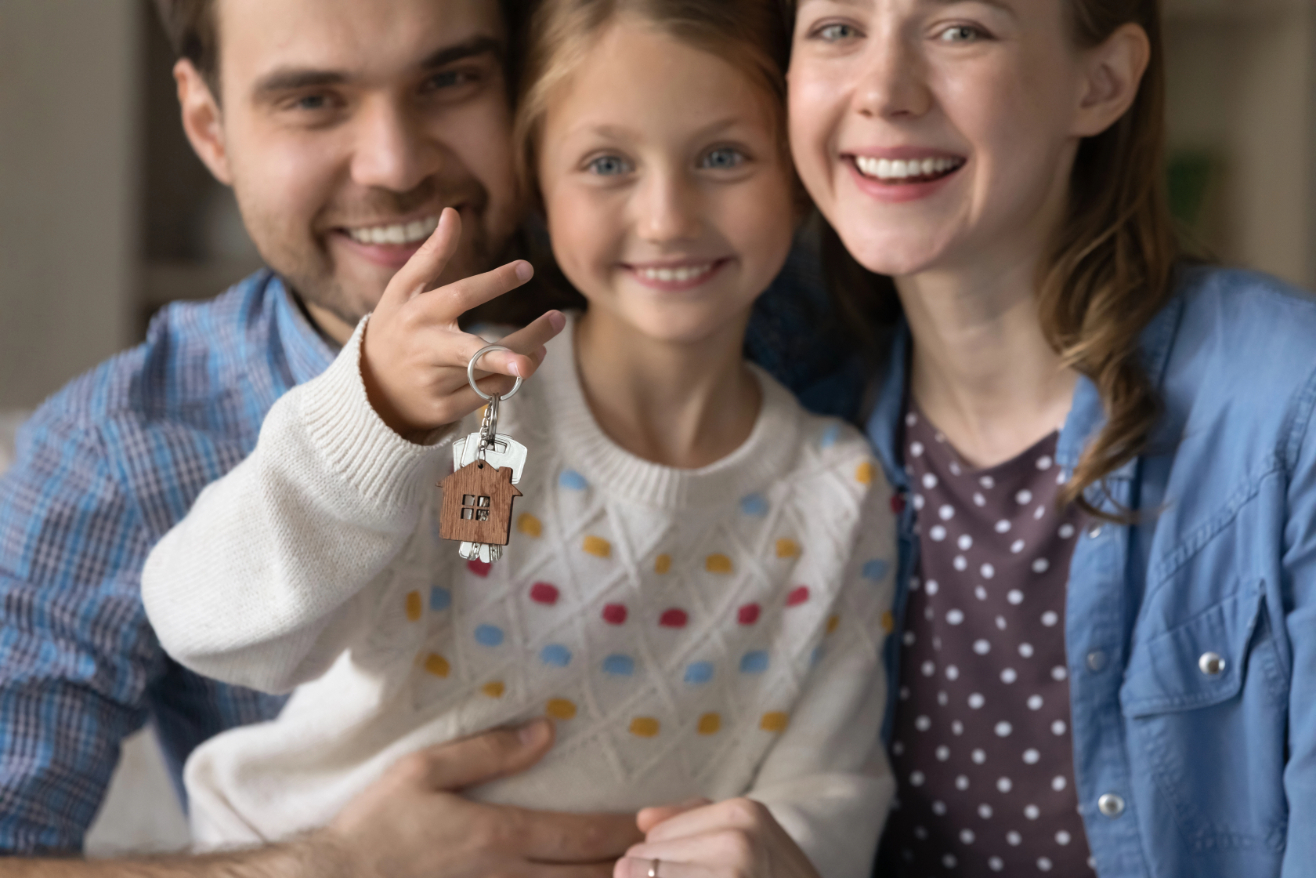 Happy couple of parents and sweet daughter kid holding keys